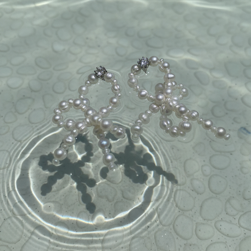 Pearl necklace on a textured surface with water reflections