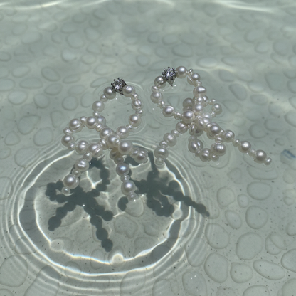 Pearl necklace on a textured surface with water reflections
