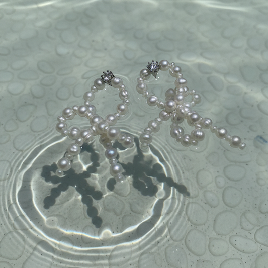 Pearl necklace on a textured surface with water reflections