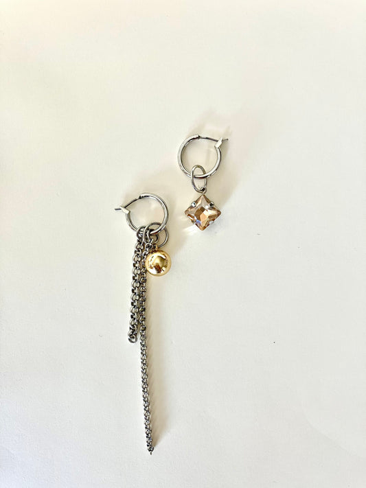 Pair of earrings with chain and round pendants on a light background