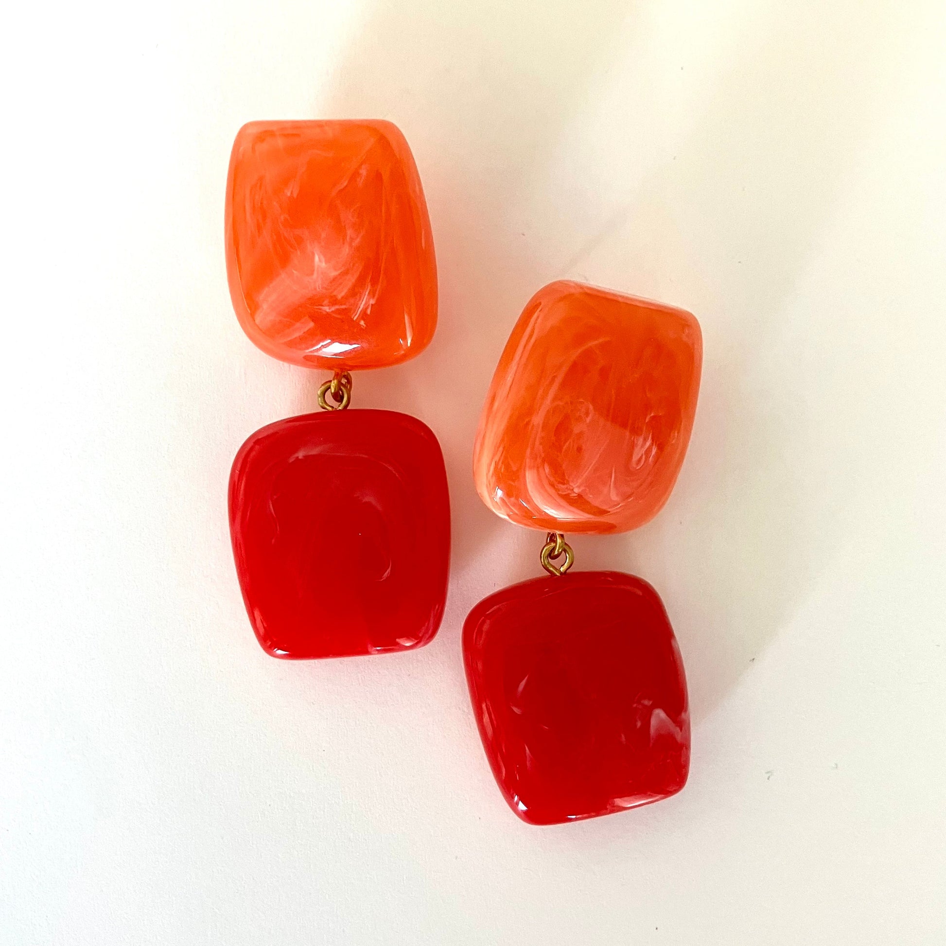 Pair of red and orange earrings on a white background