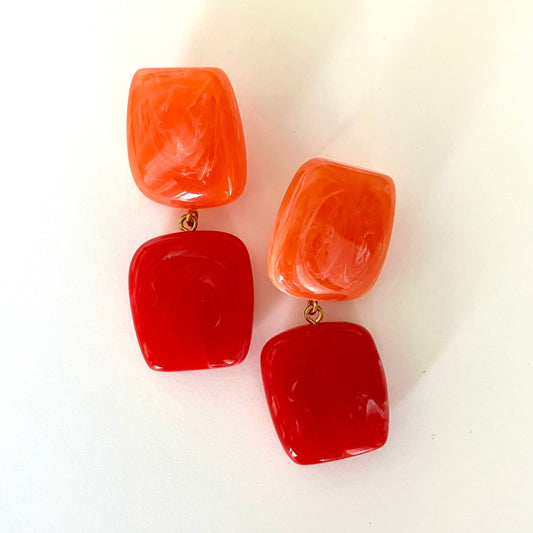 Pair of red and orange earrings on a white background
