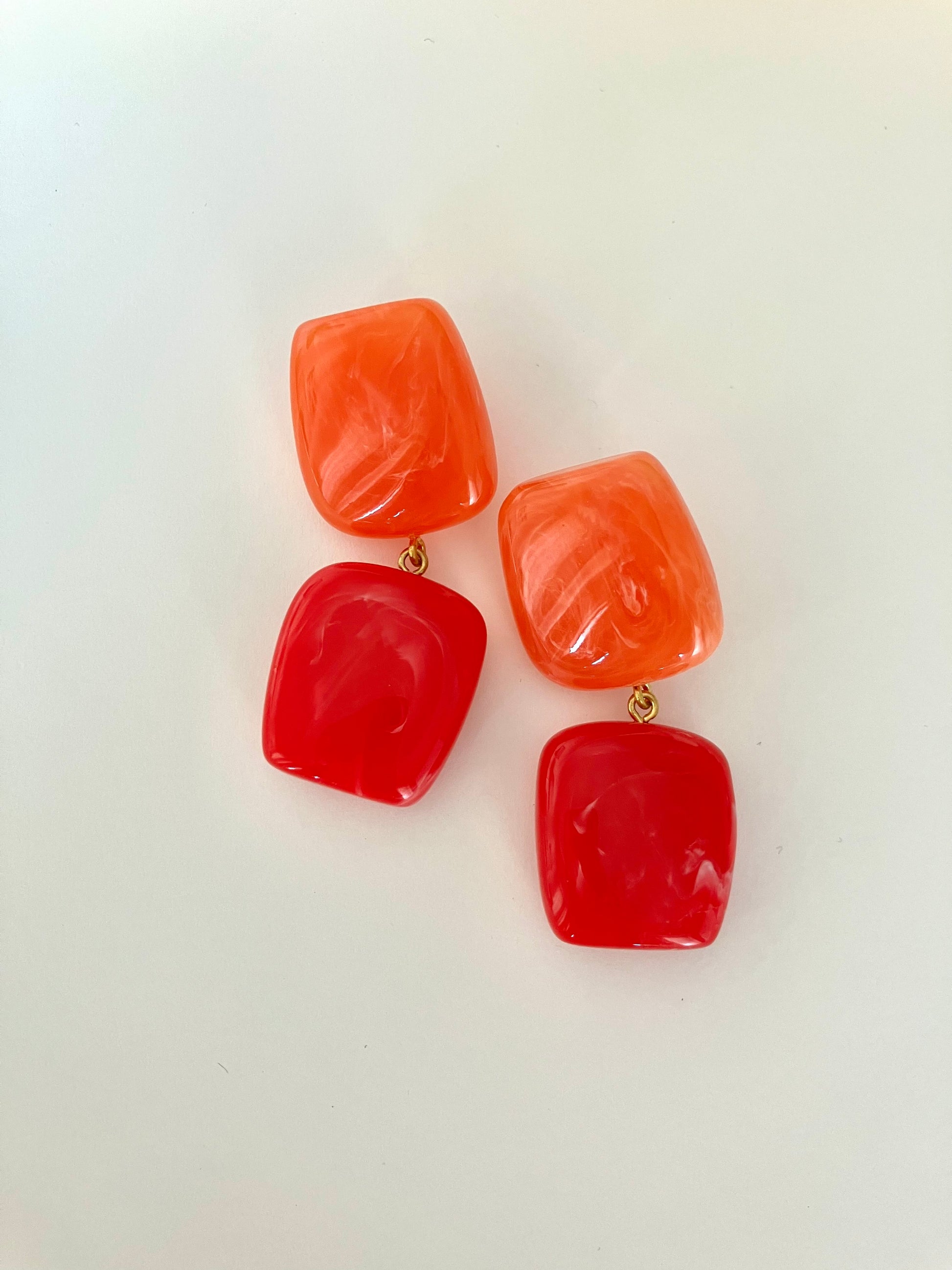 Pair of red and orange square-shaped earrings on a white background
