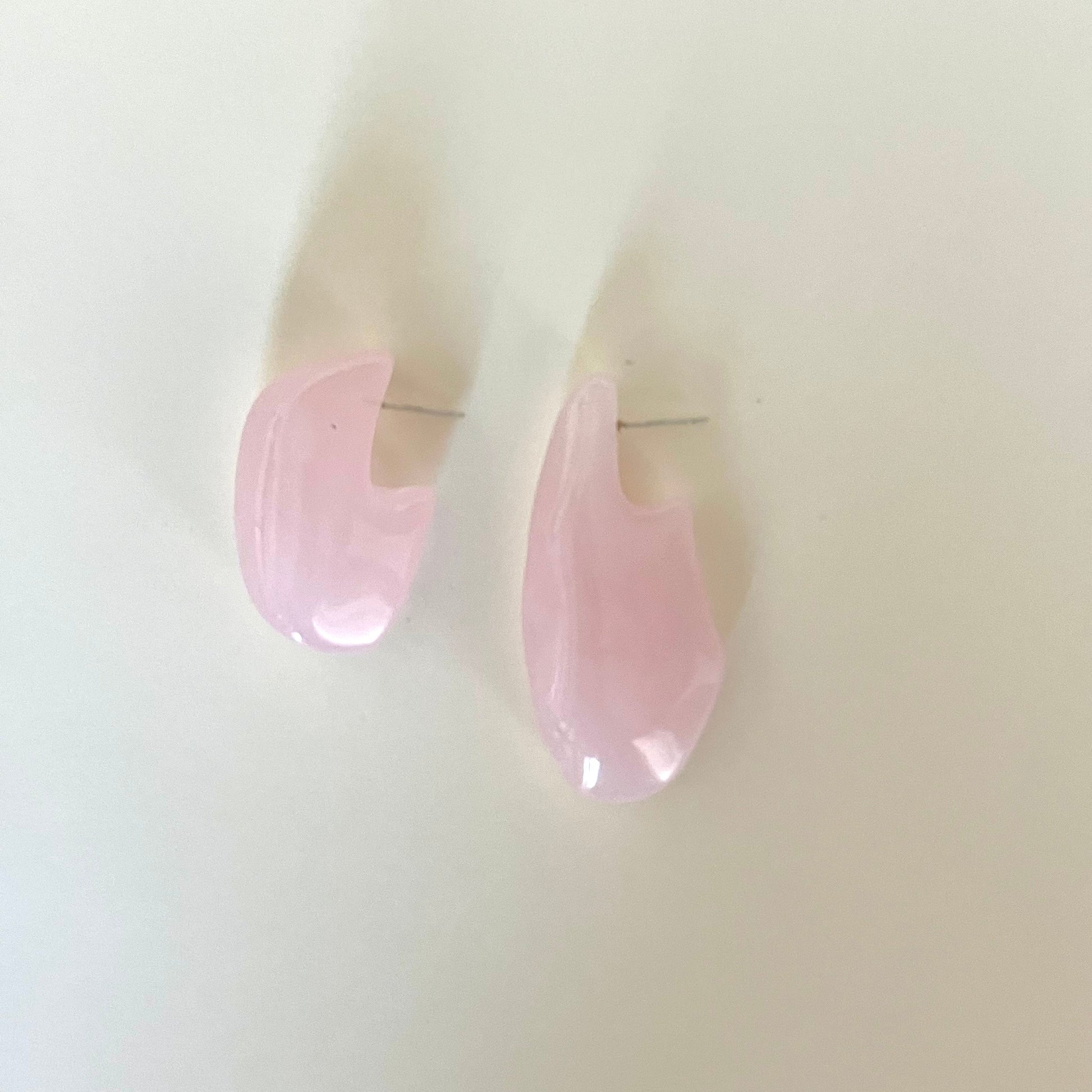 Pink teardrop-shaped earrings on a light beige background