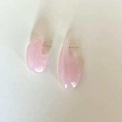 Pink teardrop-shaped earrings on a light beige background