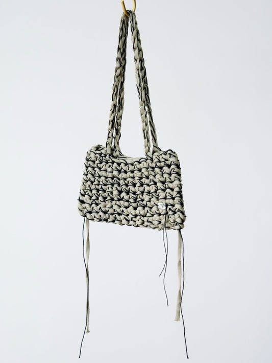 Woven handbag with long straps on a white background