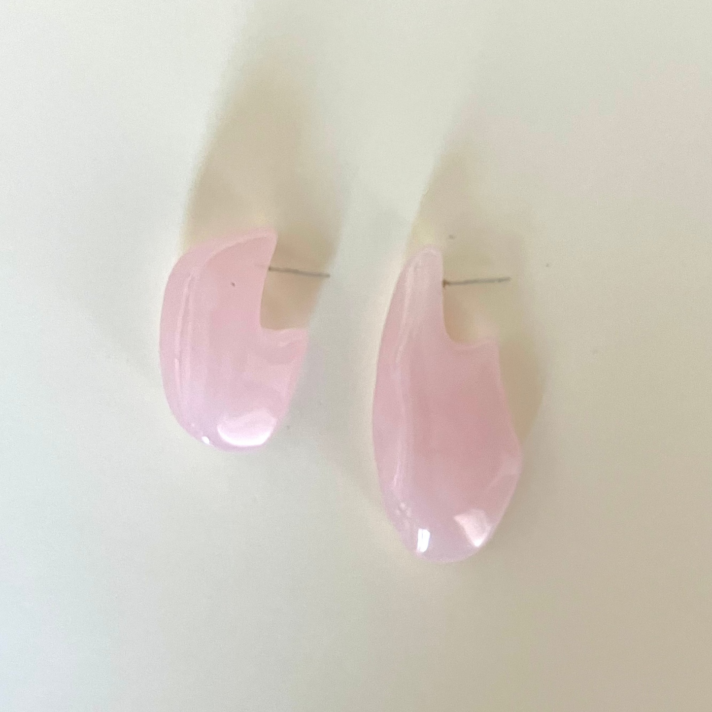 Pink teardrop-shaped earrings on a light beige background