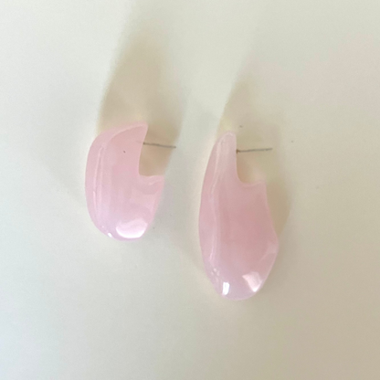 Pink teardrop-shaped earrings on a light beige background