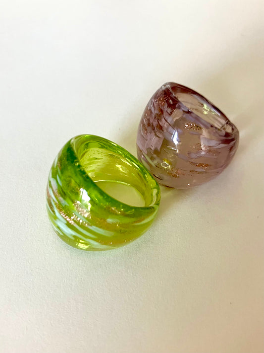 Two glass rings, one green and one brown, on a white background