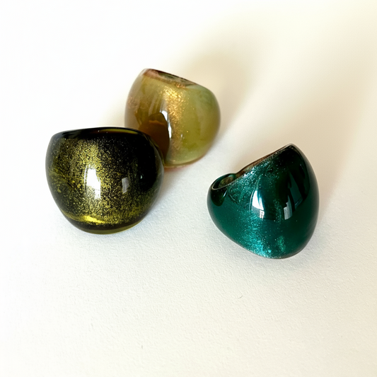 Three metallic green and gold objects on a white background